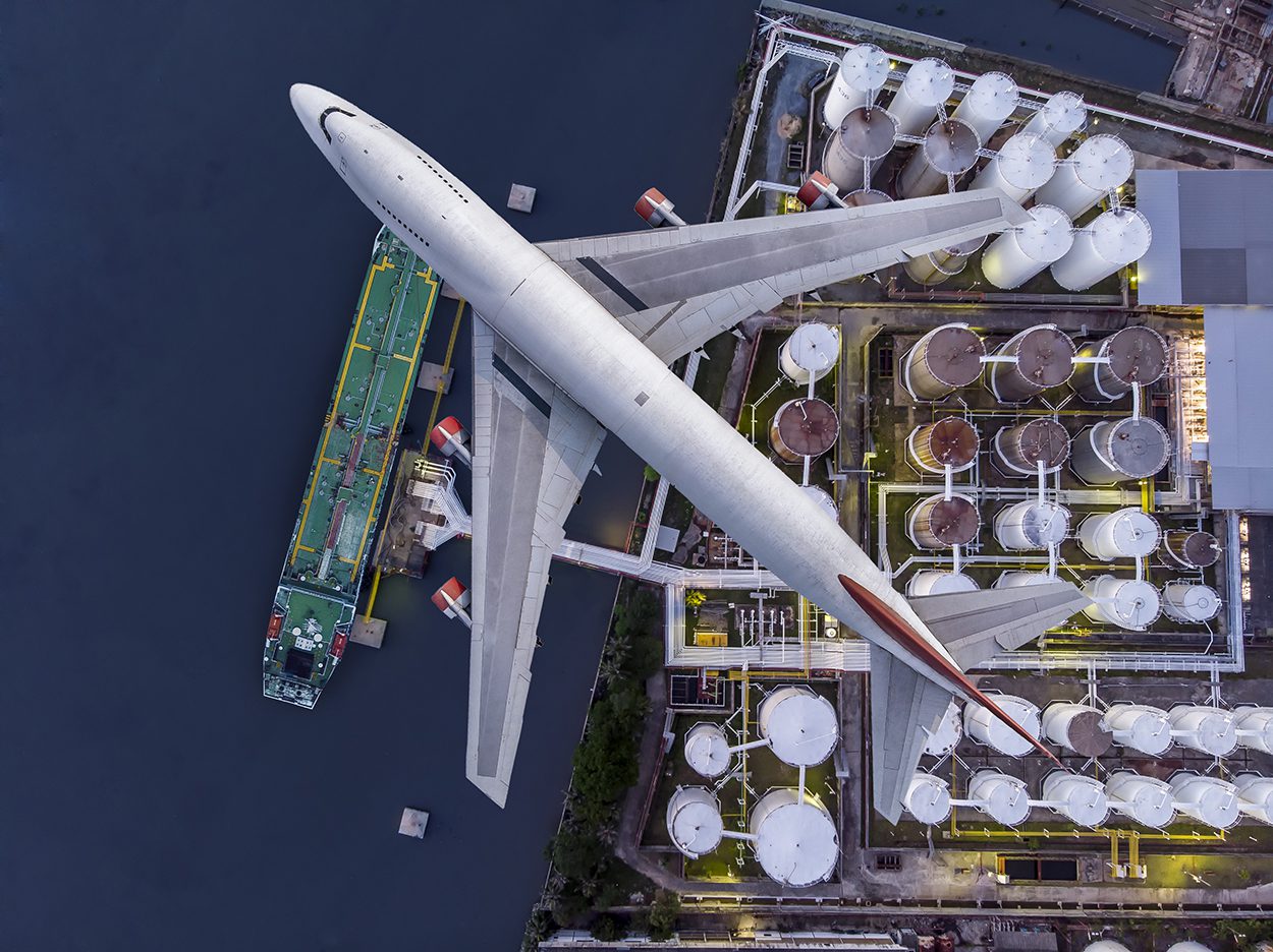 Αεροφωτογραφία που δείχνει αεροπλάνα που πετούν πάνω από μια μεγάλη αποθήκη πετρελαίου.