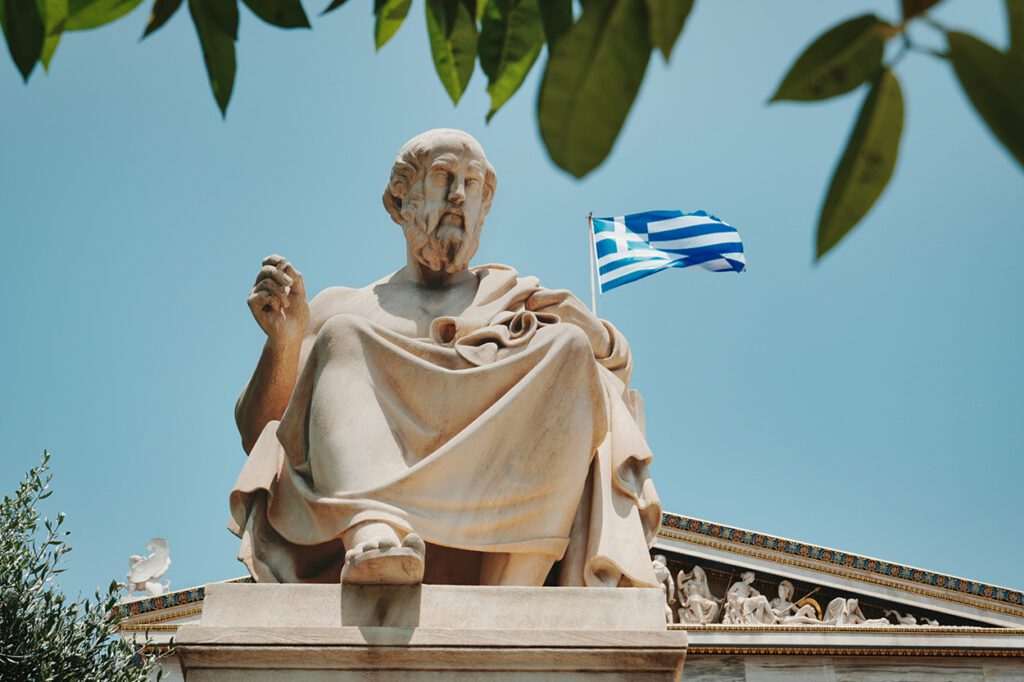 Άγαλμα του Πλάτωνα με την ελληνική σημαία να διακρίνεται στο φόντο