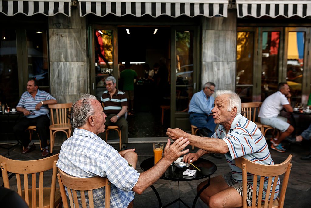 Local residents gesticulate as they speak to one another at a cafe terrace in Athens, Greece, on Friday, July 17, 2015. Germany's Parliament is set to ratify bridge financing and the start of talks for a three-year rescue plan. Photographer: Yorgos Karahalis/Bloomberg via Getty Images