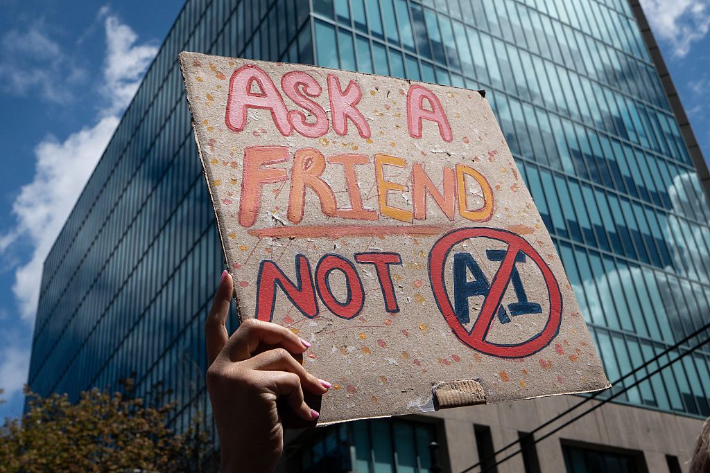 Πλακάτ σε διαδήλωση κατά των data centers που γράφει Ask a friend not AI