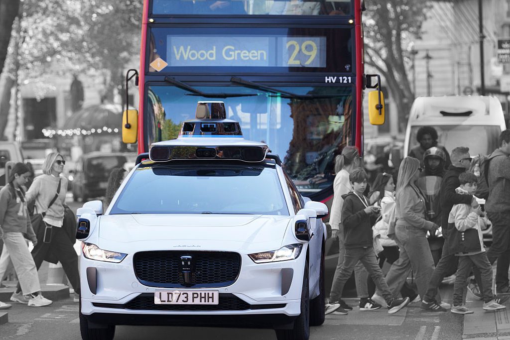 Pedestrians cross Charing Cross Road, behind A Waymo self-driving Jaguar robotaxi in the West End, on 23rd April 2026, in London, England. Waymo are testing their vehicles around the capital using a driver at the wheel. Waymo say they're not yet offering commercial rides, but instead testing 24/7 to ensure their technology can safely handle all of London's road conditions. (Photo by Richard Baker / In Pictures via Getty Images)